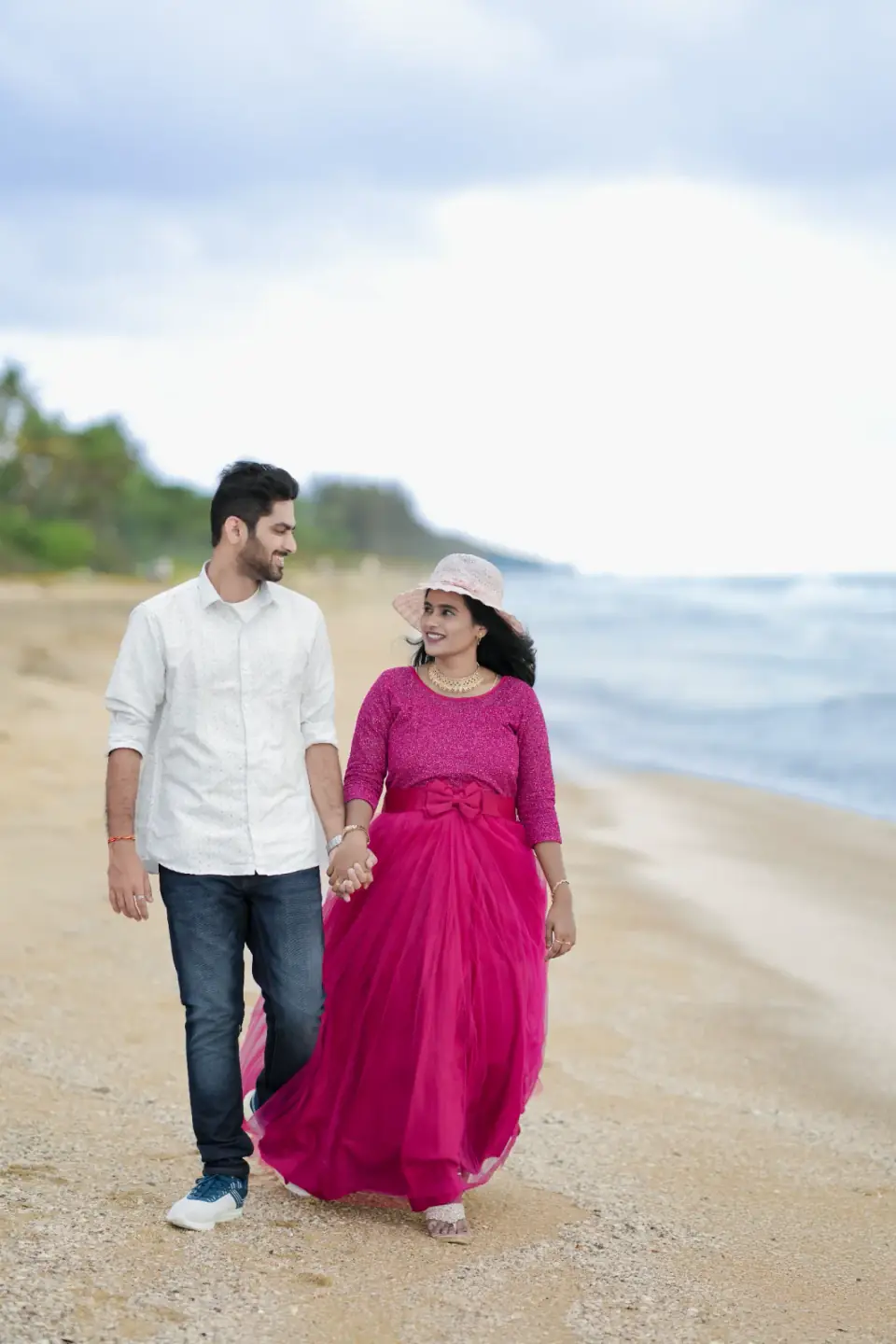 Couple in pink and white strolling along the shoreline