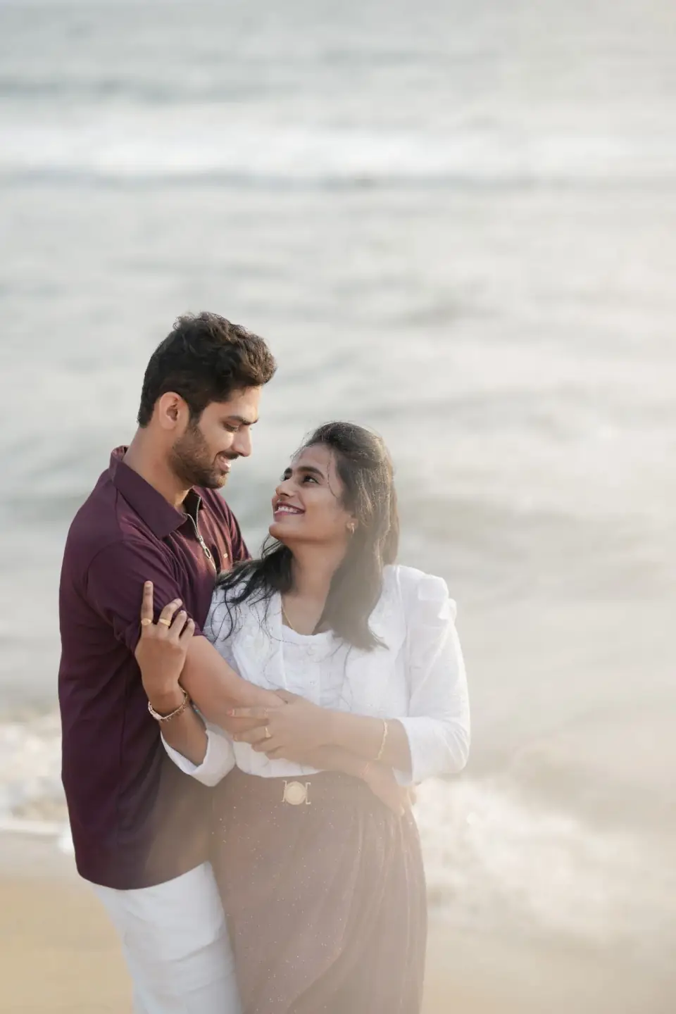 Couple embracing by the sea during a beach pre-wedding shoot