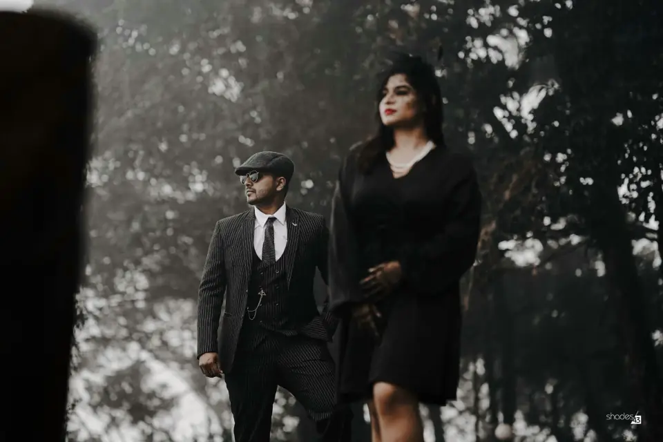 Black and white pre-wedding portrait of a couple in formal wear among trees