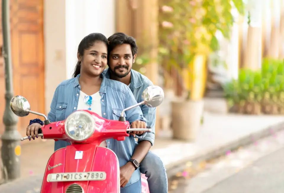 Smiling couple on a red scooter, playful pre-wedding shoot