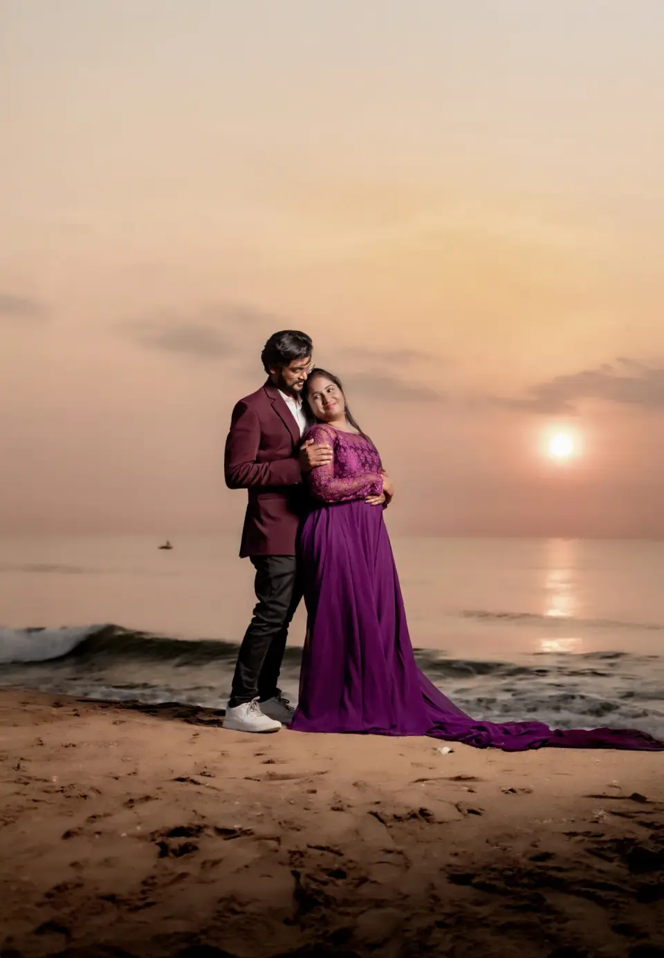 Couple embracing in front of a golden sunrise over the sea